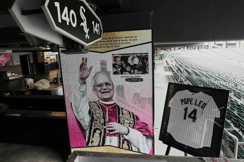 A colorful portrait of Pope Leo XIV waving appears on a wall next to a framed White Sox jersey featuring his name on its back