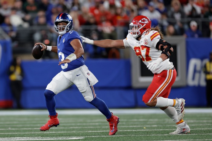 Russell Wilson escapes the pressure from a defensive end who is reaching for him and attempts a pass.