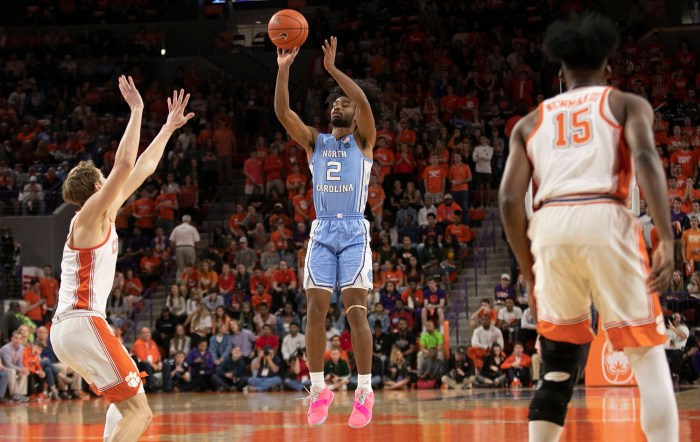Coby White attempts a 3-point shot for North Carolina as a defender puts his hands up.