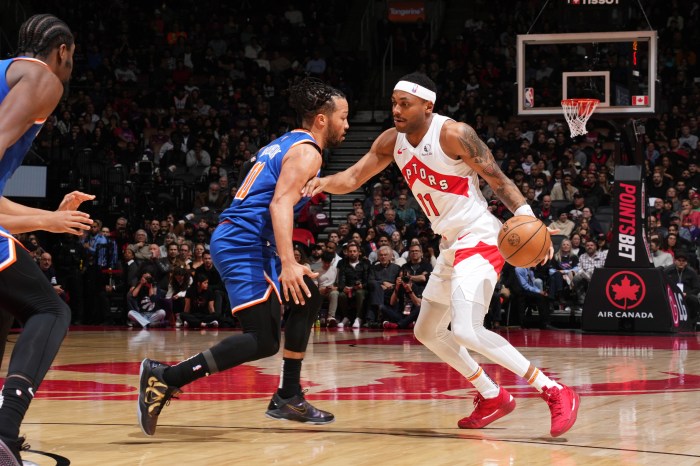 Bruce Brown handles the ball with his left hand while brushing off a New York Knicks defender with his right hand.