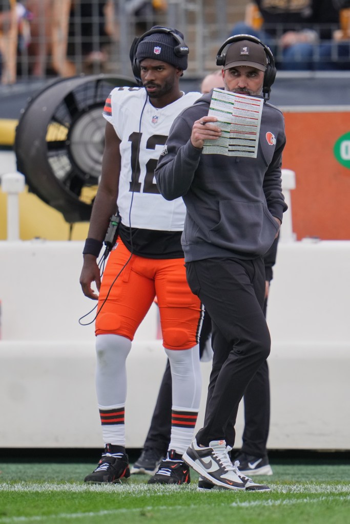 Cleveland Browns head coach Kevin Stefanski walks on the sidelines past quarterback Shedeur Sanders, who is wearing a headset.